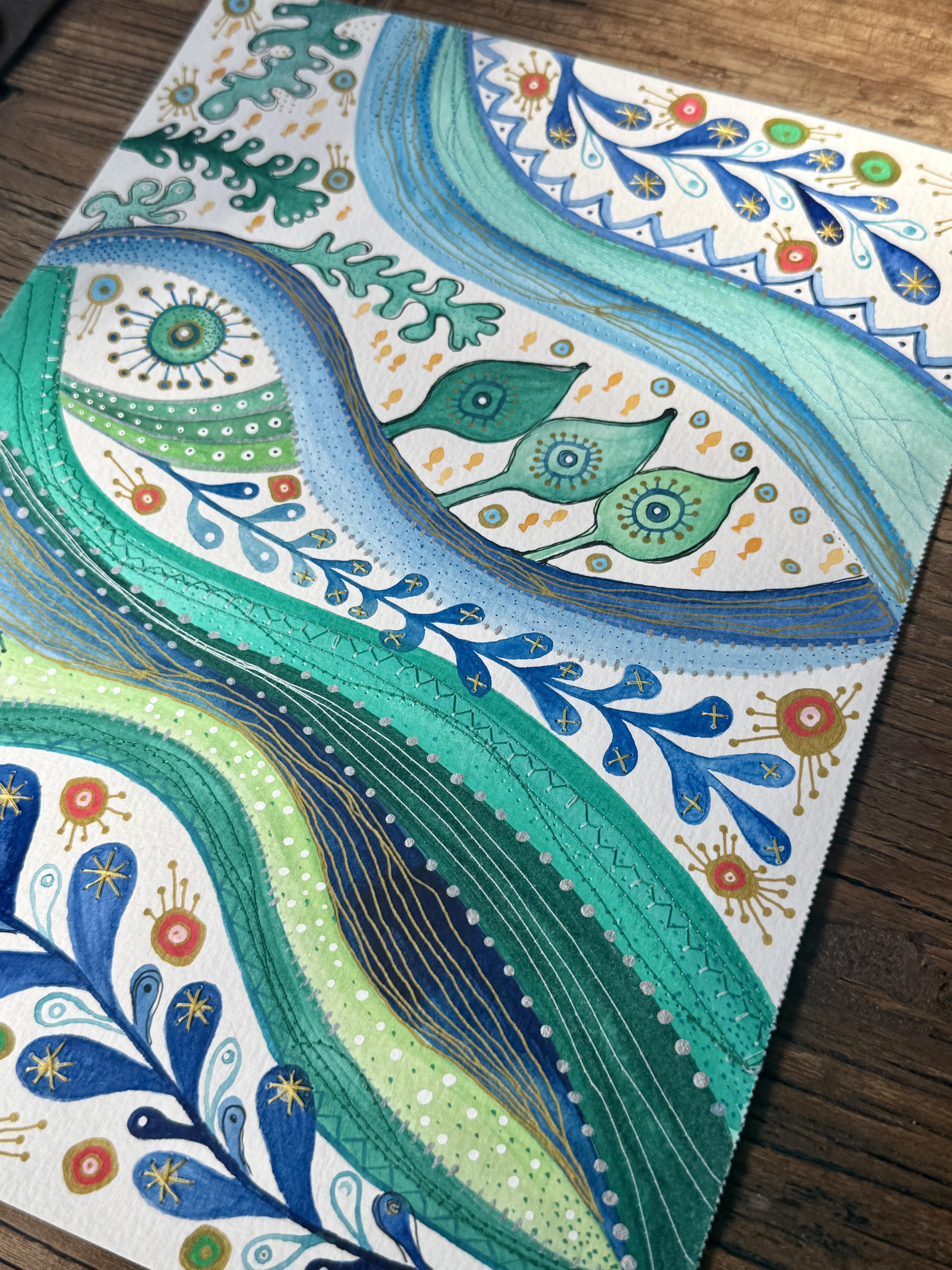 River watercolor with stitched gold stars and paisley motifs