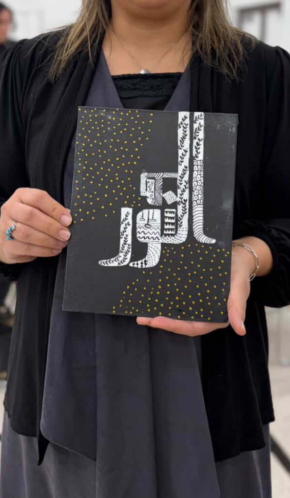 Participant holding a finished canvas with gold dotwork