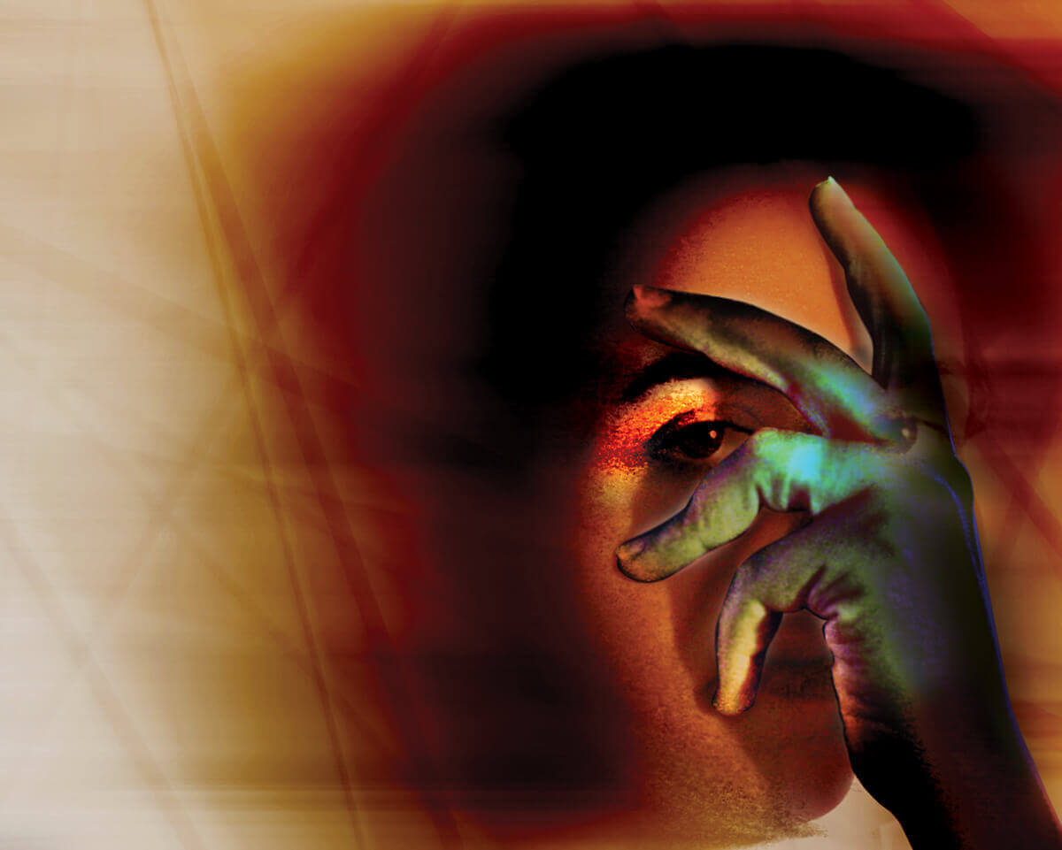 Eye seen between fingers held across a face